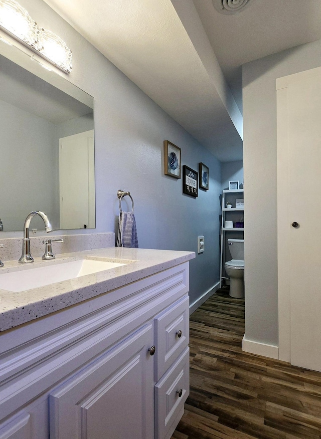 22004 Old Curry Rd SE, Cass Lake, MN 56633 - bathroom featuring wood finished floors, vanity, toilet, and baseboards