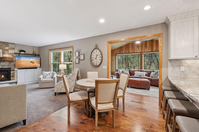dining area featuring recessed lighting, visible vents, a stone fireplace, and light wood finished floors