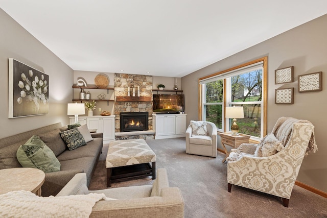 carpeted living area featuring a stone fireplace