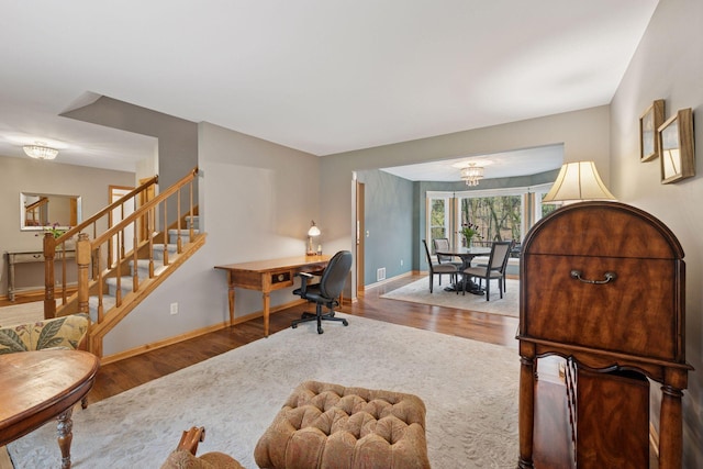 home office with baseboards, wood finished floors, and a notable chandelier