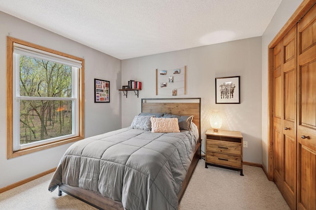 bedroom with a textured ceiling, baseboards, light colored carpet, and a closet