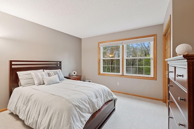 bedroom featuring baseboards, light carpet, and a textured ceiling