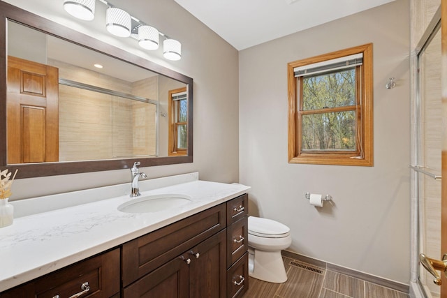 bathroom with vanity, toilet, baseboards, and a stall shower