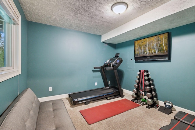 workout room with baseboards, carpet, and a textured ceiling