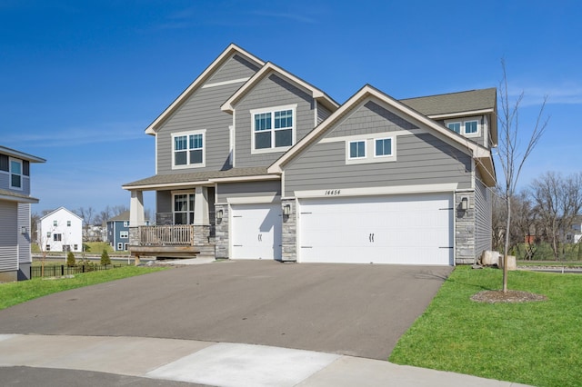 craftsman-style house featuring a garage, driveway, stone siding, and fence