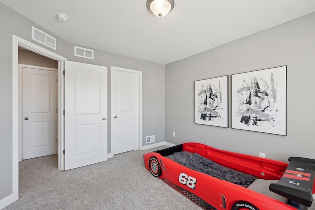 carpeted bedroom with a closet, visible vents, and baseboards