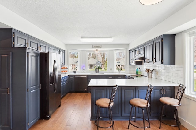 kitchen with stainless steel refrigerator with ice dispenser, a healthy amount of sunlight, a peninsula, and dishwasher