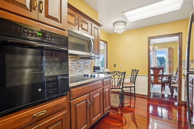 8621 Basswood Rd Unit 32, Eden Prairie, MN 55344 - kitchen featuring tasteful backsplash, black appliances, a chandelier, light stone counters, and dark wood-style floors
