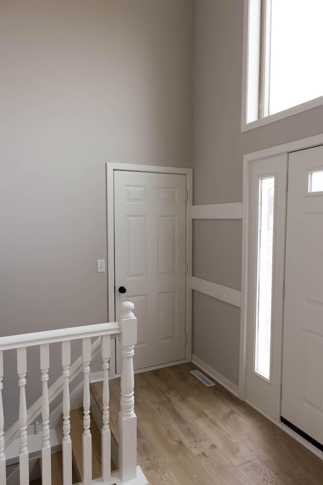 foyer entrance with visible vents, light wood-style flooring, and baseboards