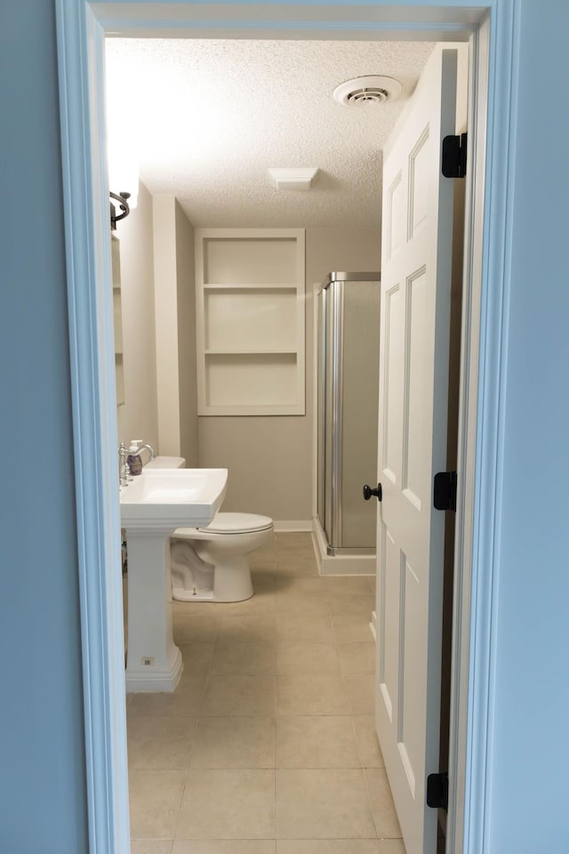 full bathroom with tile patterned floors, a textured ceiling, toilet, a shower stall, and visible vents