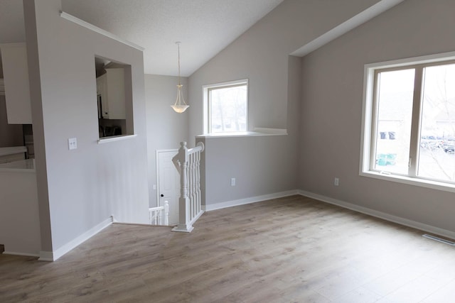 interior space with baseboards, vaulted ceiling, and wood finished floors