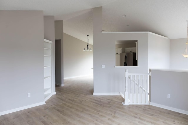unfurnished room featuring light wood finished floors, baseboards, and vaulted ceiling