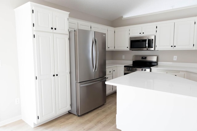 kitchen with white cabinetry, light countertops, lofted ceiling, stainless steel appliances, and light wood finished floors
