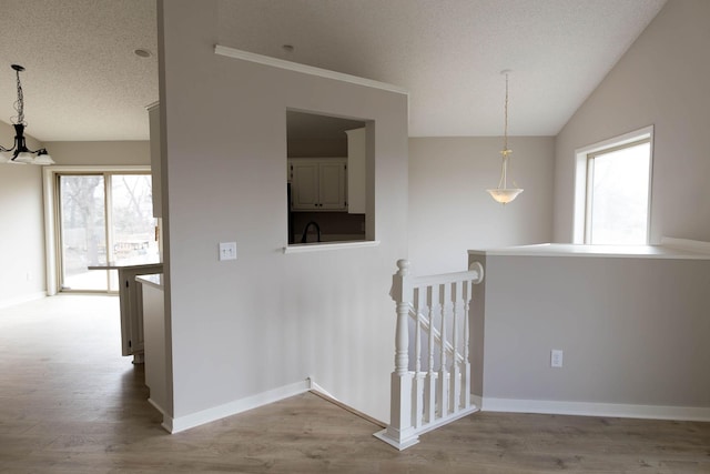 staircase with baseboards, plenty of natural light, a chandelier, and wood finished floors