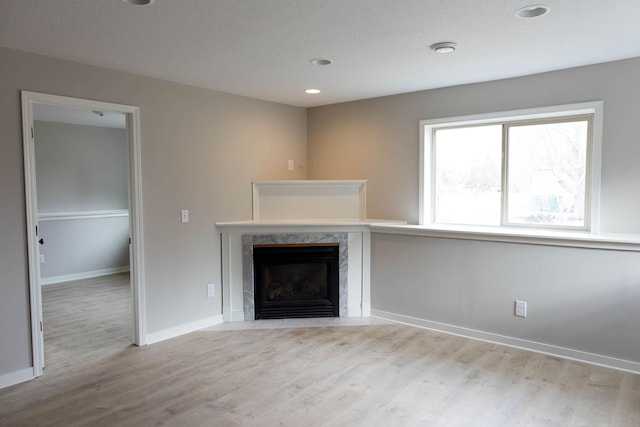 unfurnished living room with wood finished floors, a fireplace, baseboards, and recessed lighting