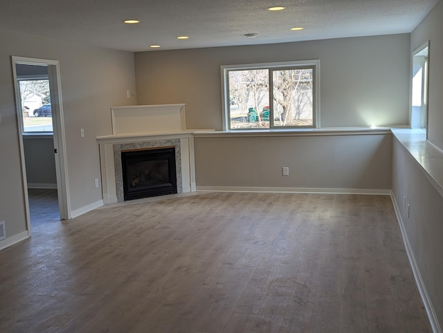 unfurnished living room with wood finished floors, a fireplace, baseboards, and recessed lighting