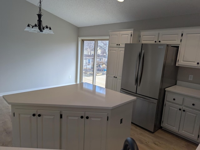 kitchen featuring light wood-style flooring, freestanding refrigerator, light countertops, and white cabinetry