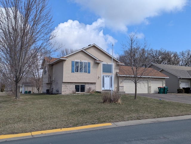 split level home with aphalt driveway, a front lawn, and an attached garage