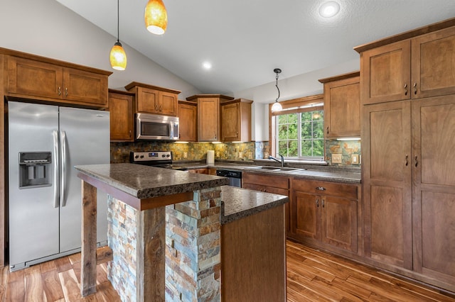 6387 203rd Ct N, Forest Lake, MN 55025 - kitchen featuring appliances with stainless steel finishes, a sink, vaulted ceiling, dark countertops, and brown cabinets