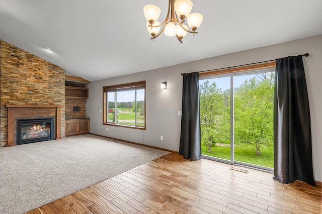 6387 203rd Ct N, Forest Lake, MN 55025 - unfurnished living room with a chandelier, lofted ceiling, wood finished floors, a glass covered fireplace, and baseboards