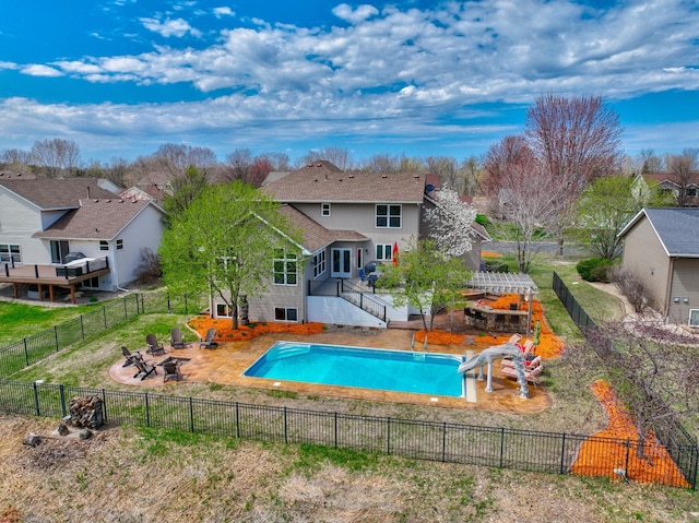 view of pool with stairway, a fenced in pool, a fenced backyard, an outdoor fire pit, and a water slide