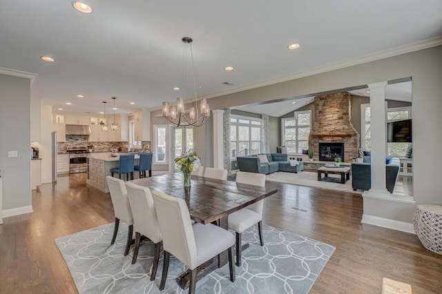 dining space featuring crown molding, a fireplace, recessed lighting, baseboards, and wood finished floors