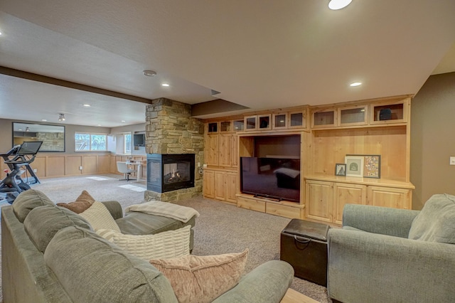 living room featuring recessed lighting, a stone fireplace, and light carpet