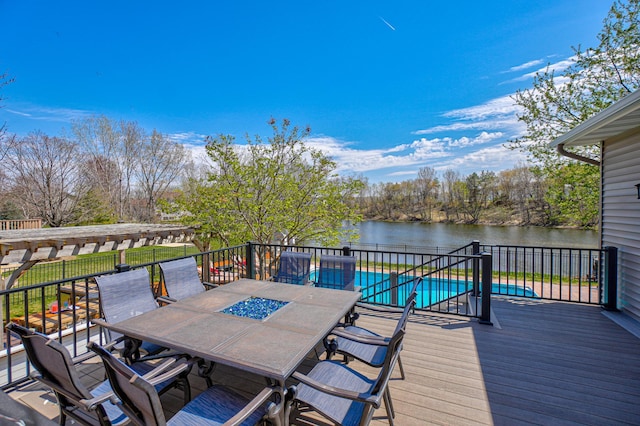 wooden deck with a fenced in pool, outdoor dining space, and a water view