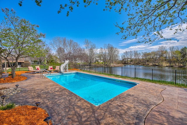 view of swimming pool with fence, a fenced in pool, a patio area, a water view, and a water slide