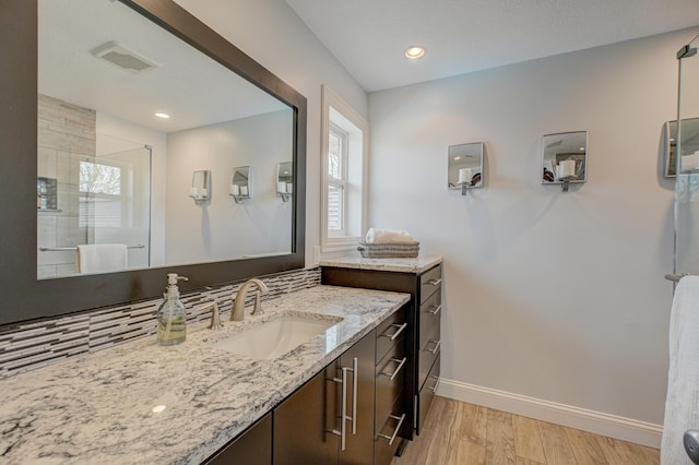 bathroom with plenty of natural light, baseboards, wood finished floors, visible vents, and a stall shower