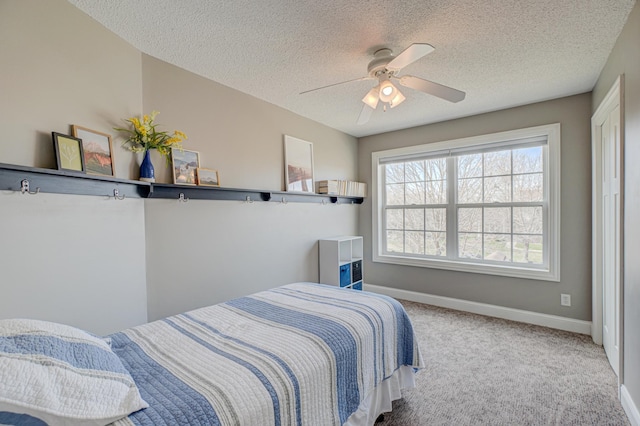 bedroom with a textured ceiling, baseboards, ceiling fan, and carpet