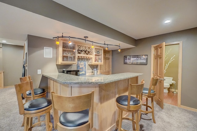 bar featuring bar, light colored carpet, rail lighting, baseboards, and recessed lighting