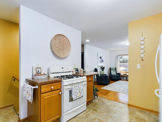 kitchen with baseboards, open floor plan, white appliances, dark countertops, and brown cabinets