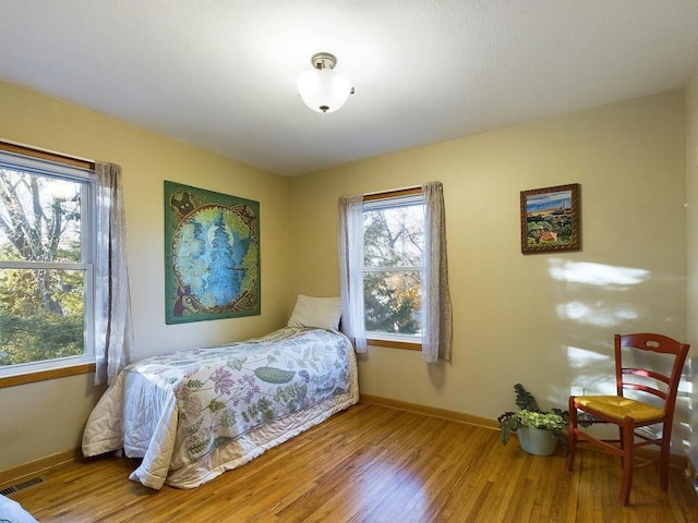 bedroom featuring visible vents, baseboards, and wood finished floors