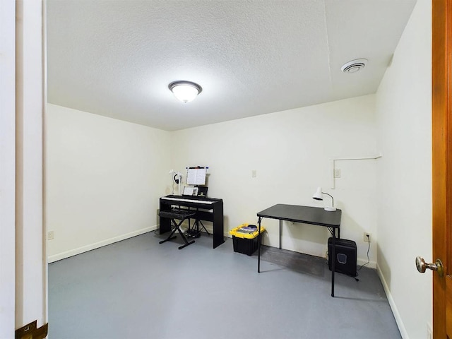 misc room with finished concrete floors, visible vents, baseboards, and a textured ceiling
