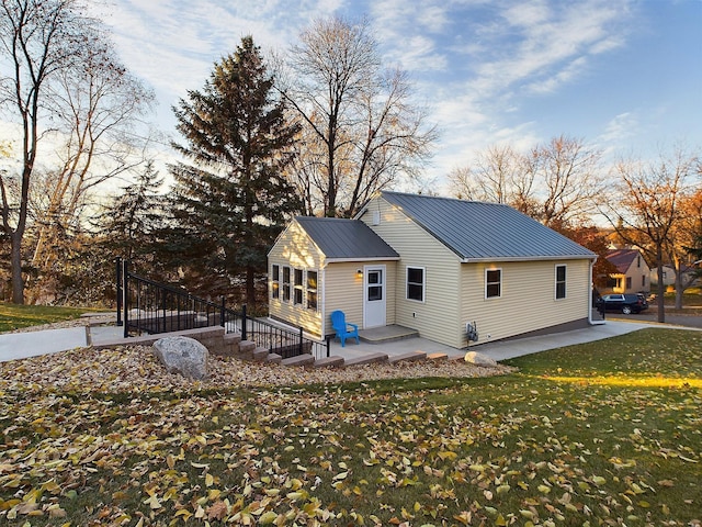 back of house with a yard, a patio area, and metal roof