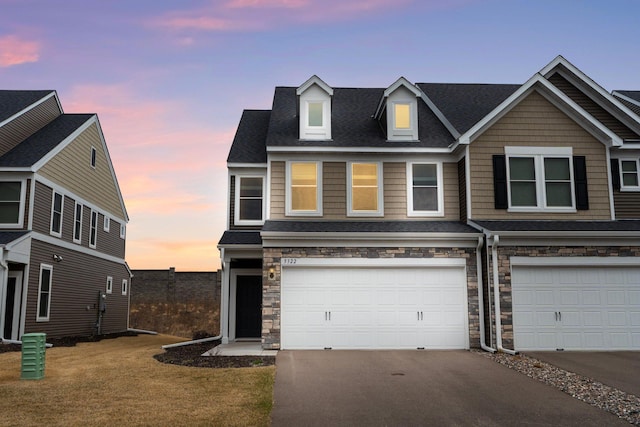 view of front of house with an attached garage, driveway, and stone siding