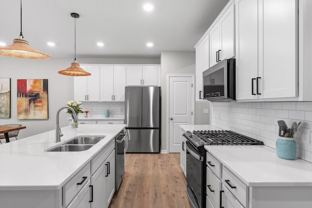 kitchen featuring recessed lighting, backsplash, stainless steel appliances, light wood finished floors, and a sink