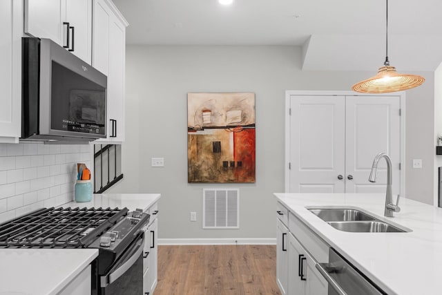 kitchen featuring visible vents, appliances with stainless steel finishes, light countertops, a sink, and backsplash