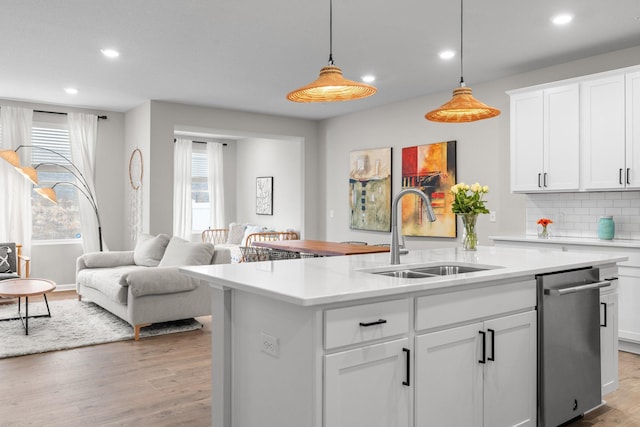 kitchen with recessed lighting, a center island with sink, light countertops, and a sink