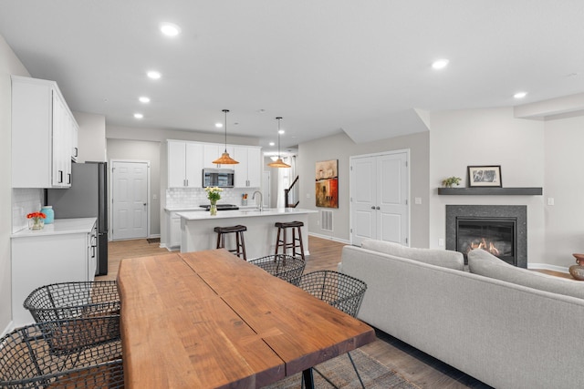 dining room featuring light wood finished floors, a glass covered fireplace, and recessed lighting