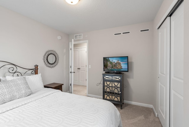 bedroom featuring a closet, light colored carpet, baseboards, and visible vents