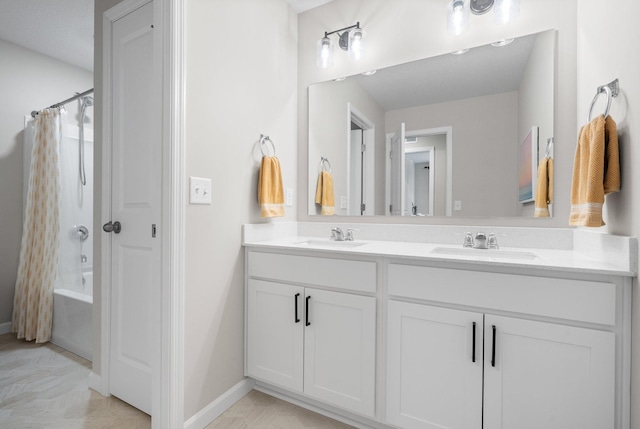 bathroom with double vanity, baseboards, a sink, and shower / bath combo with shower curtain