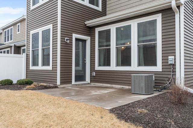 doorway to property with a patio area, cooling unit, and fence