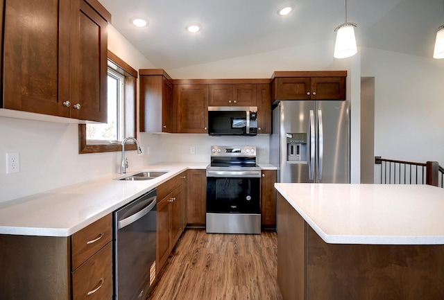 kitchen featuring lofted ceiling, stainless steel appliances, light countertops, a sink, and light wood-style floors