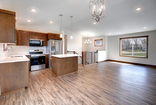 kitchen featuring a center island, a sink, light wood-style floors, stainless steel appliances, and a notable chandelier