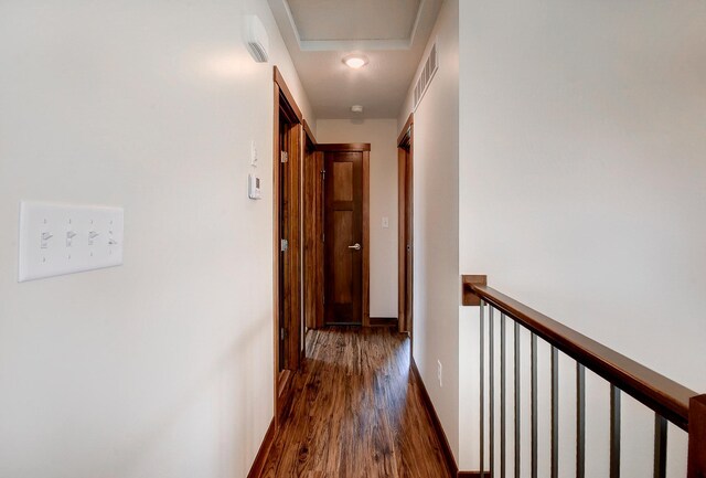 corridor with an upstairs landing, baseboards, and wood finished floors