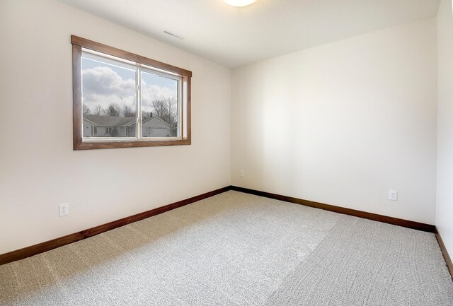 carpeted spare room with visible vents and baseboards