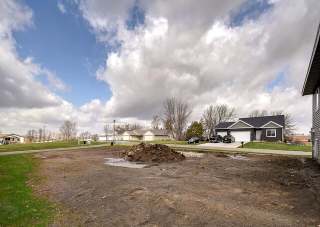 view of yard with an attached garage, driveway, and a residential view