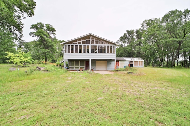 21682 Rebel Rd, Center Twp, MN 56465 - back of house with a sunroom, an attached garage, a lawn, driveway, and view of scattered trees